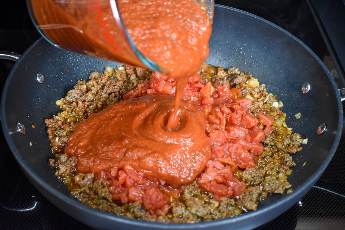 Pasta sauce being added to the browned ground beef.