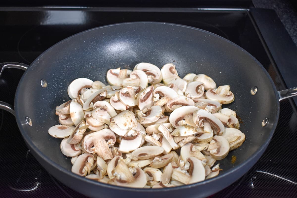 Sliced mushroom in a large, non-stick skillet before cooking down.