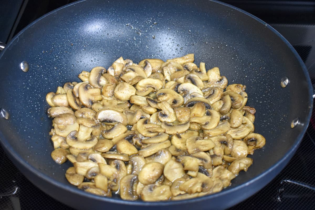 Sliced mushroom in a large, non-stick skillet after cooking.