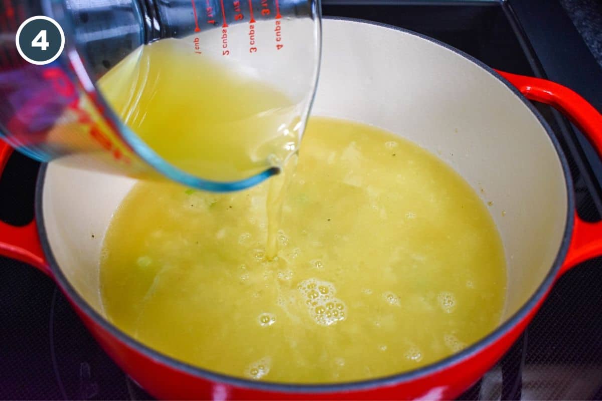 Pouring chicken broth into the pot with the roux and vegetables.
