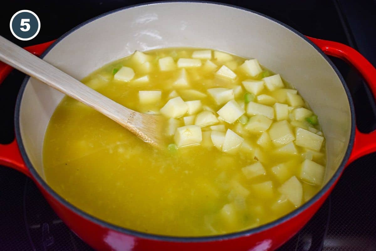 Adding diced potatoes to the simmering broth.