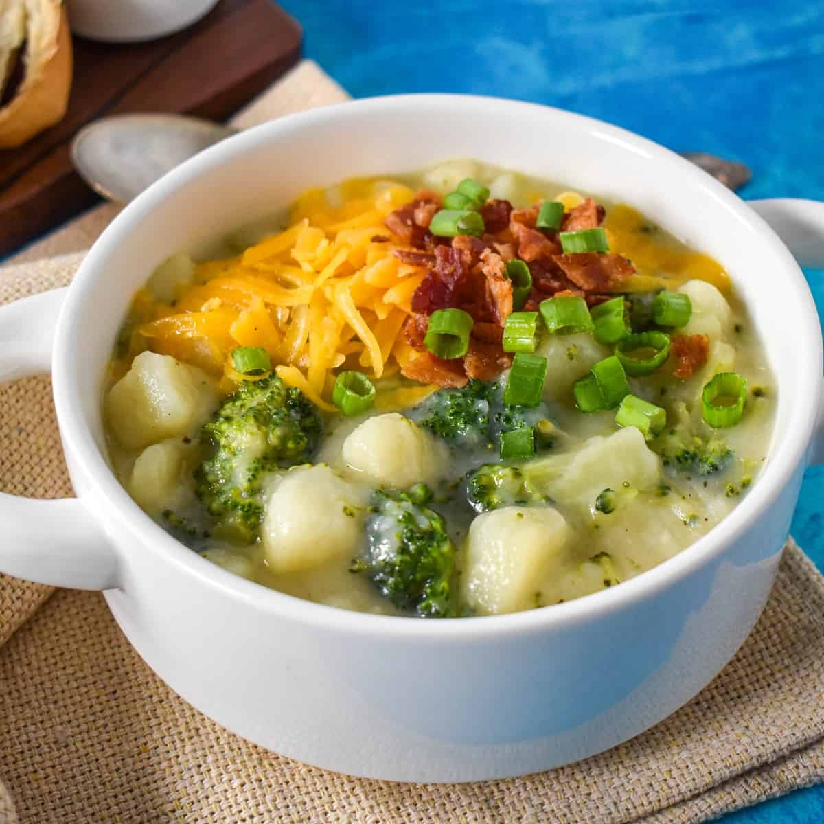 A close-up of the soup garnished with the cheese, bacon, and green onions served in a white bowl.