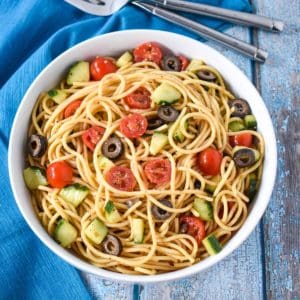 Spaghetti pasta salad served in a white bowl with a blue linen.