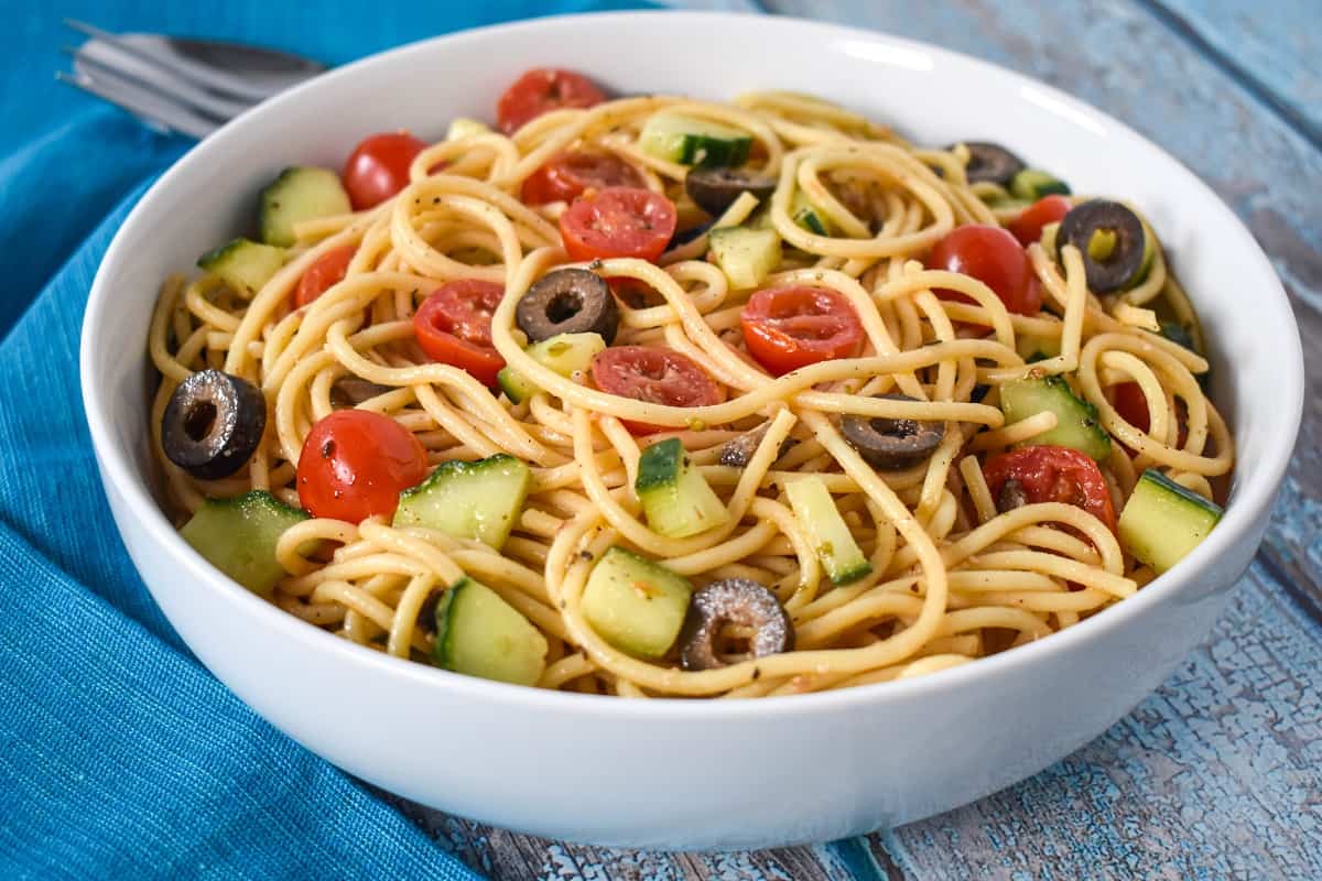 Spaghetti pasta salad served in a white bowl with a blue linen.