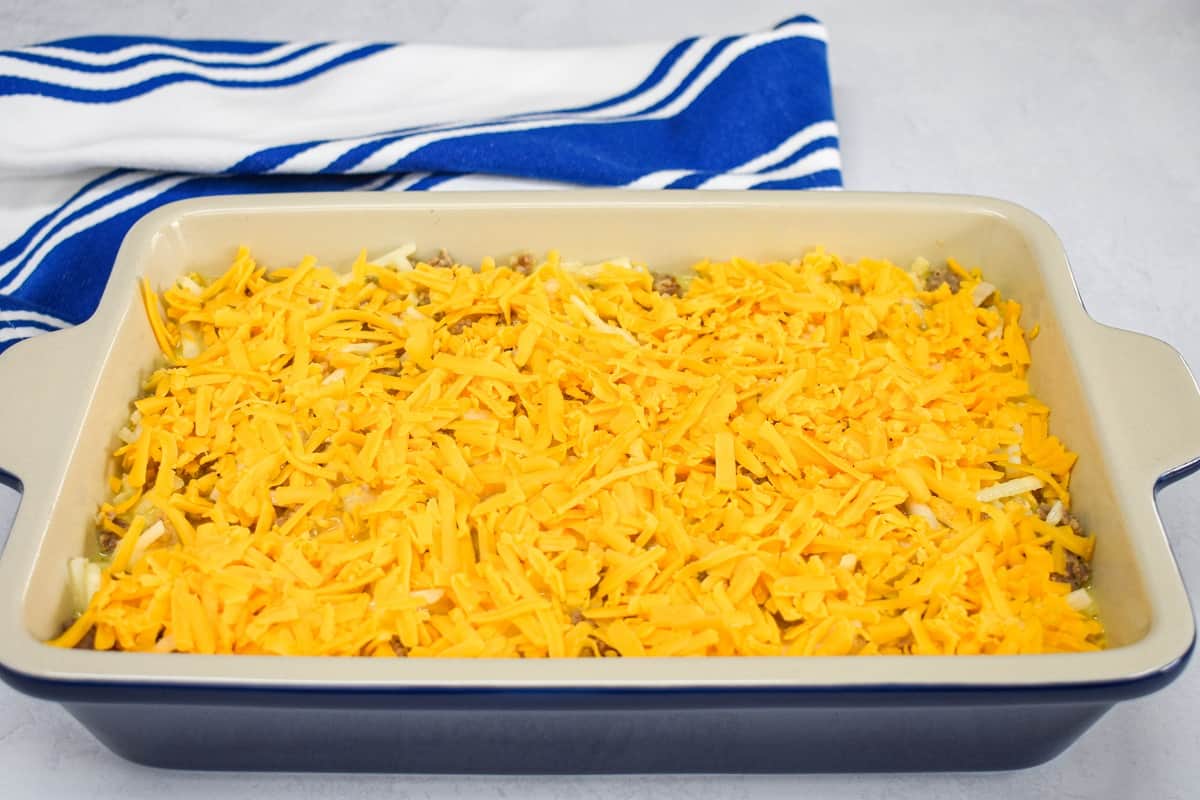 Shredded cheddar cheese sprinkled on top of the ingredients in the baking dish.