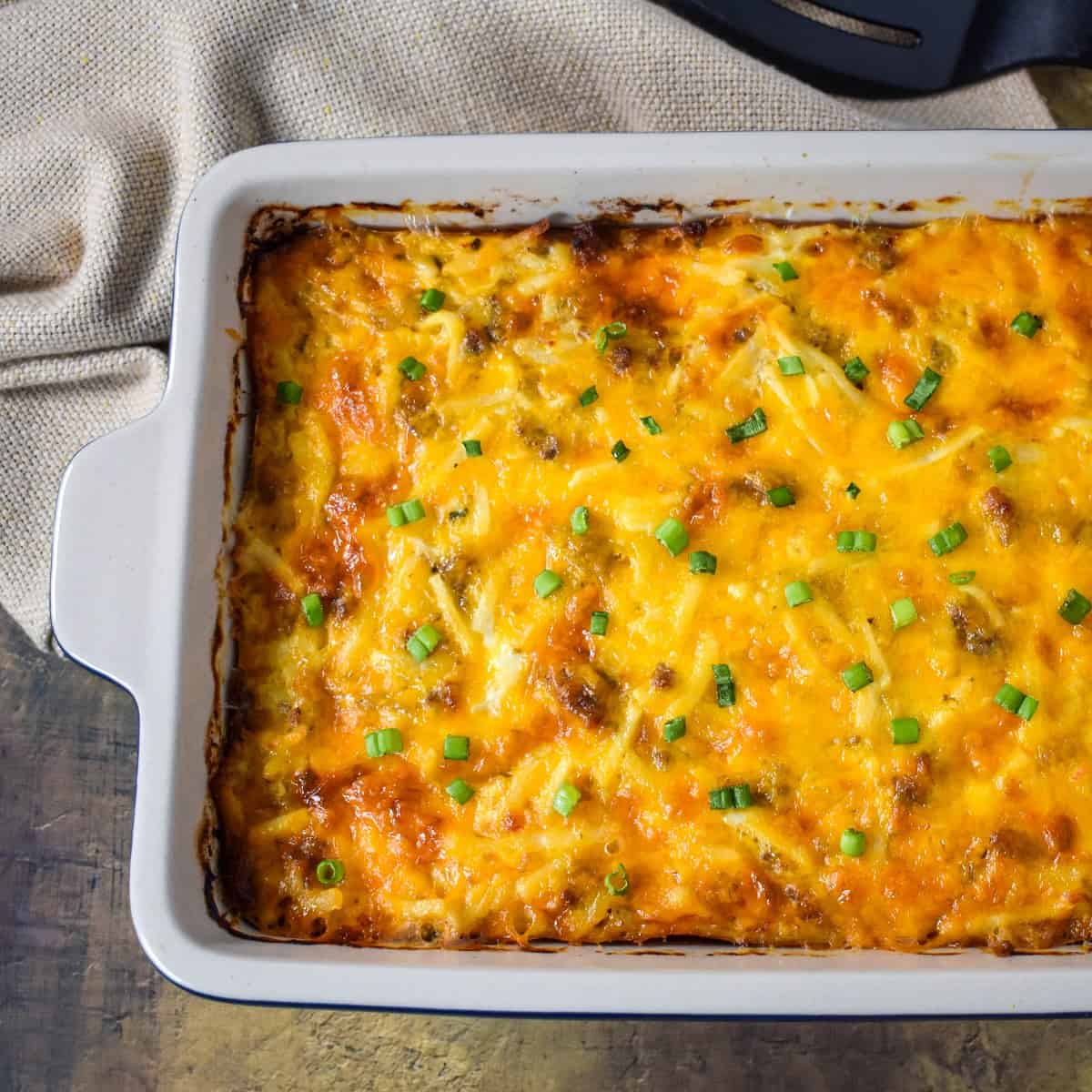 The finished sausage hash brown casserole garnished with sliced green onions.