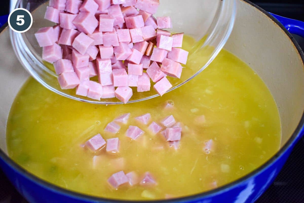 Diced cooked ham being added to the pot of broth and vegetables.