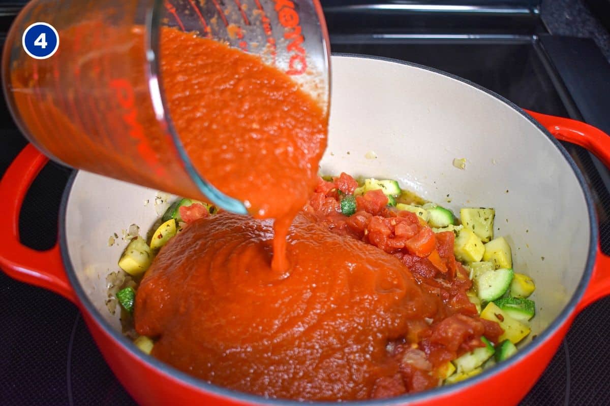 Pasta red sauce being added to the ingredients in the pot.