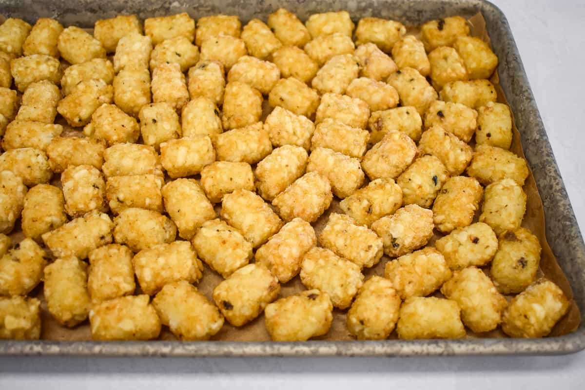 Frozen tater tots on a sheet pan lined with parchment paper.