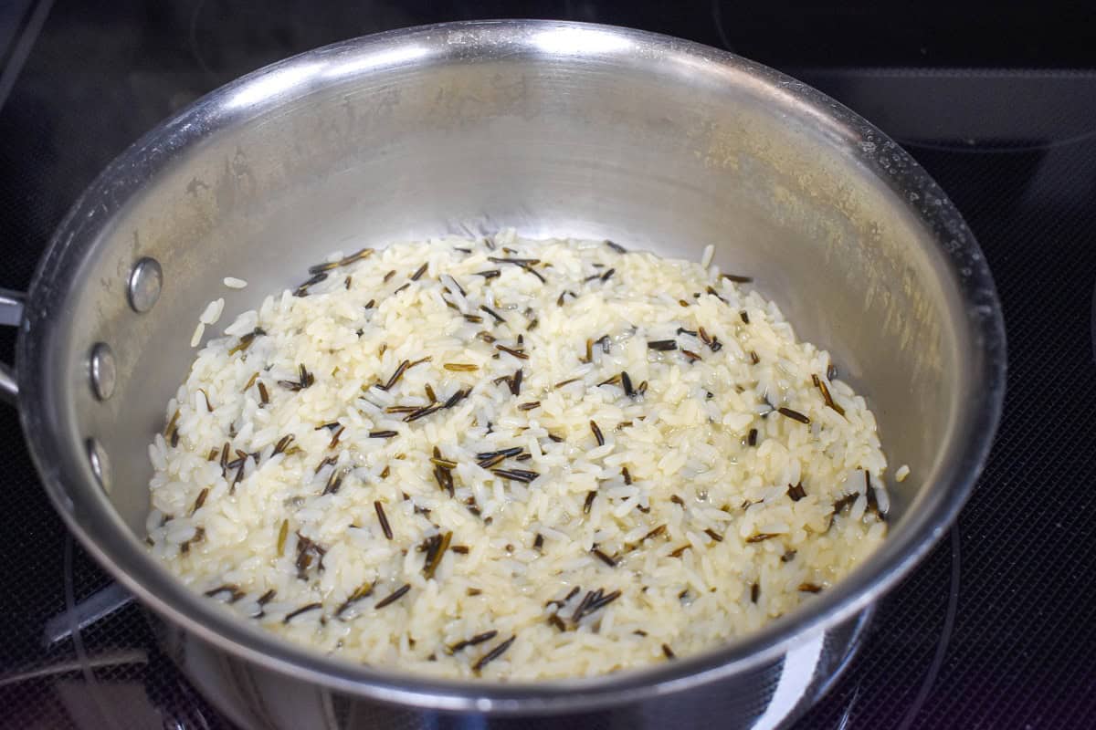 Long grain white rice and wild rice cooking in a pan.