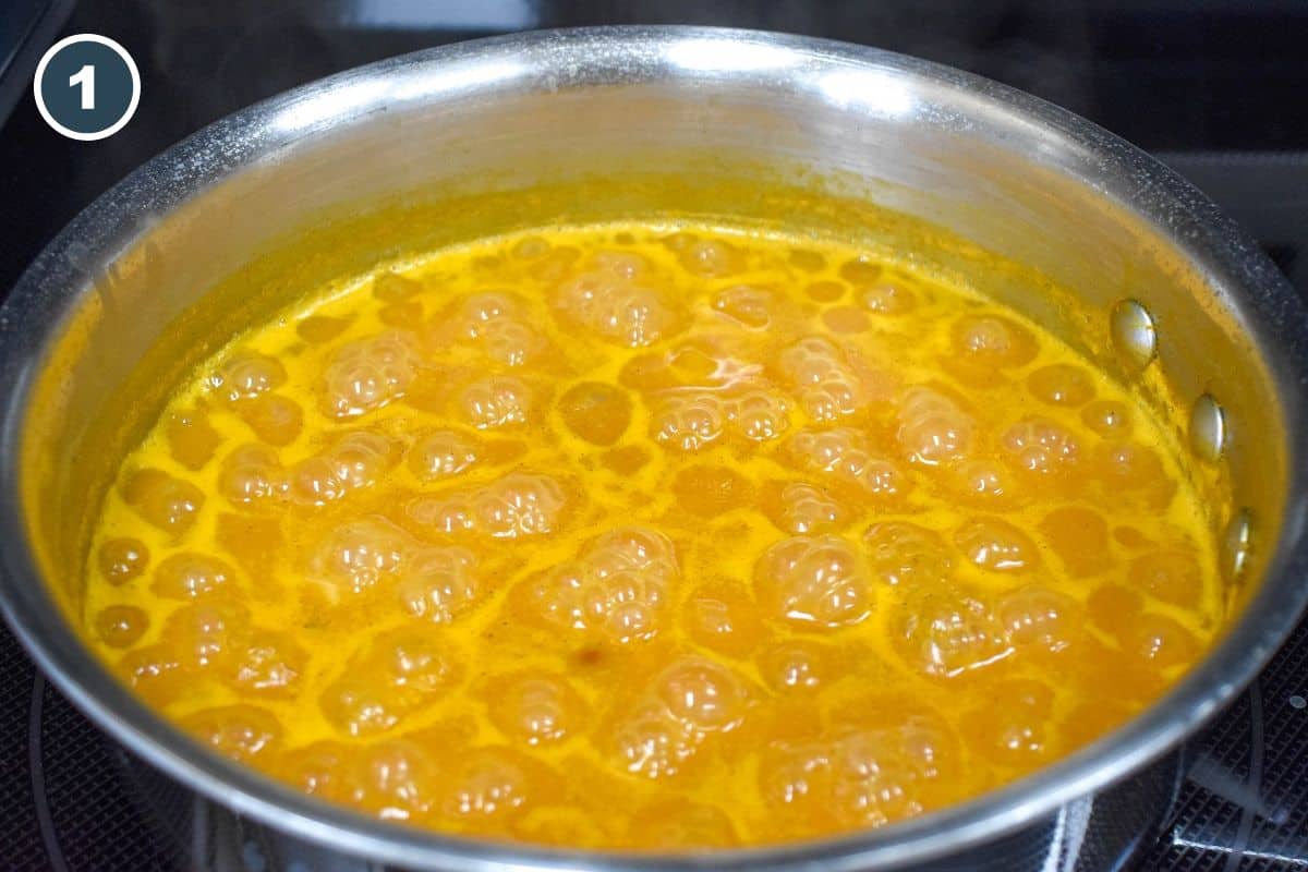 Seasoned yellow broth boiling in a saucepan.