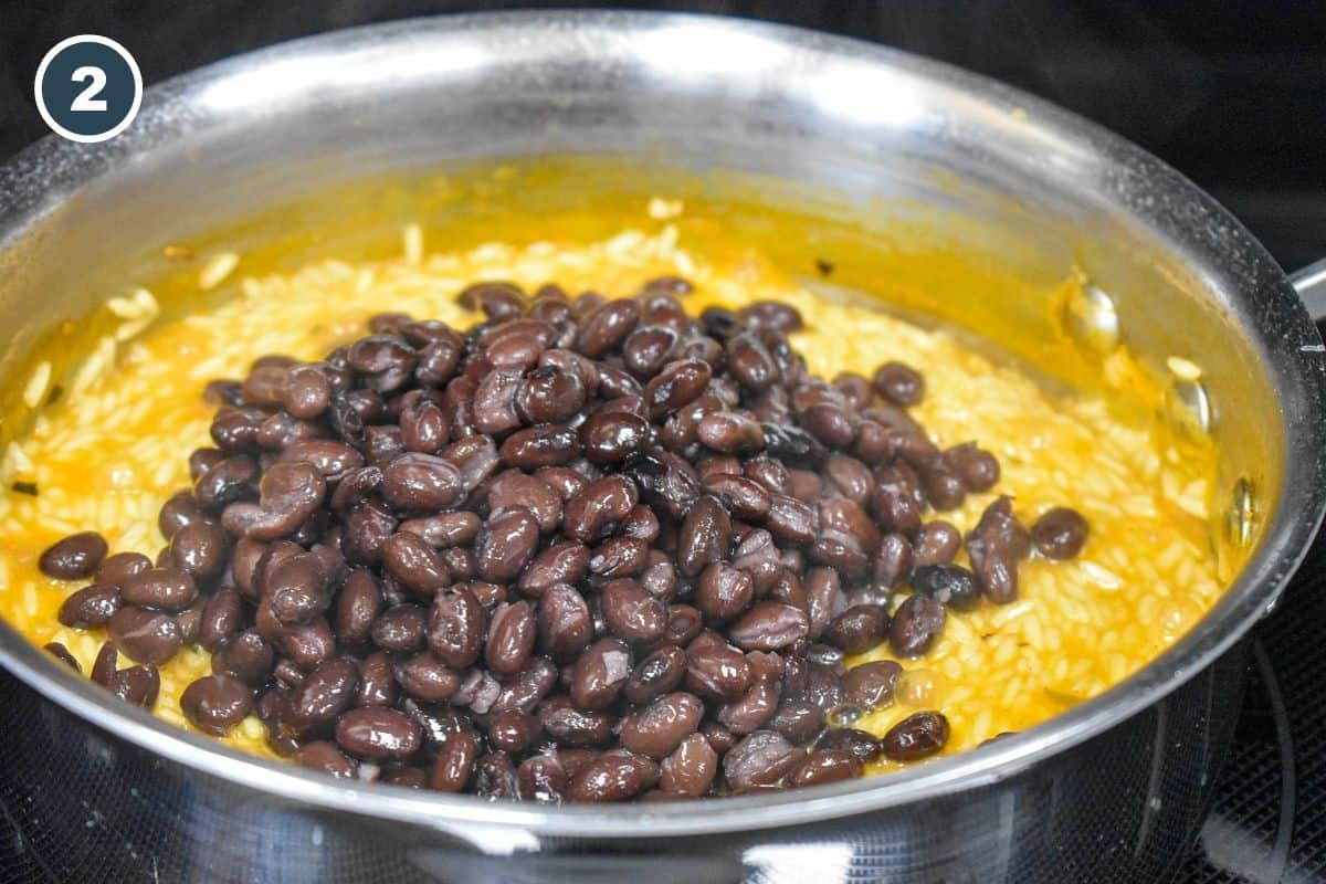 Black beans added to partially cooked yellow rice before the final simmer.