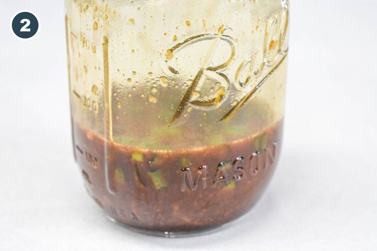 Homemade sesame chicken sauce mixed in a mason jar with green onions and seasonings.