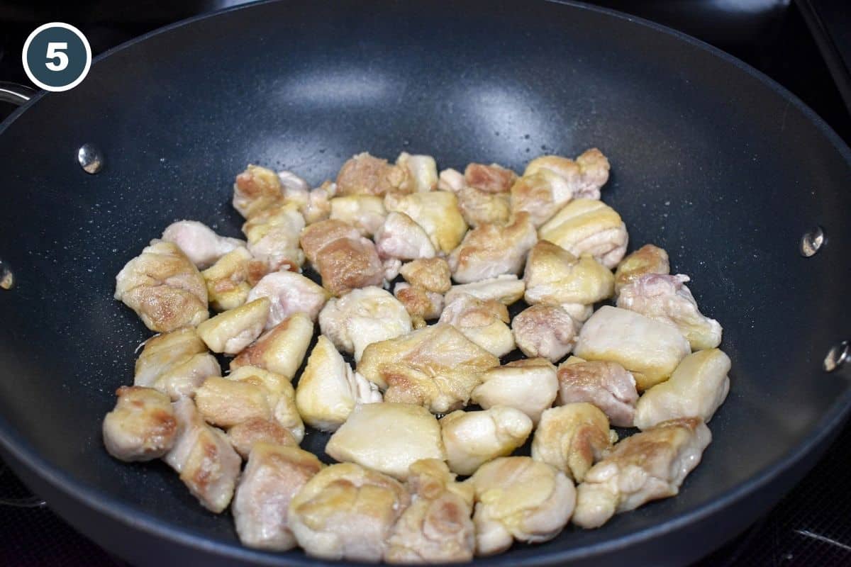Bite-sized chicken thigh pieces lightly browned in a skillet while making sesame chicken.