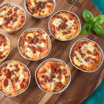 The individual pizza pot pies arranged on a wood board with a sprig of basil.