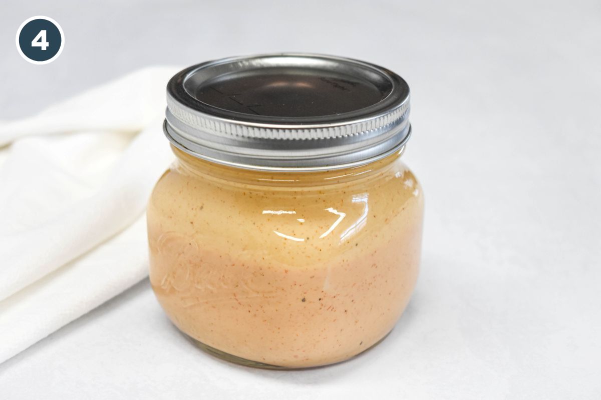 Creamy dressing in a small mason jar with the lid on, ready for the fridge.