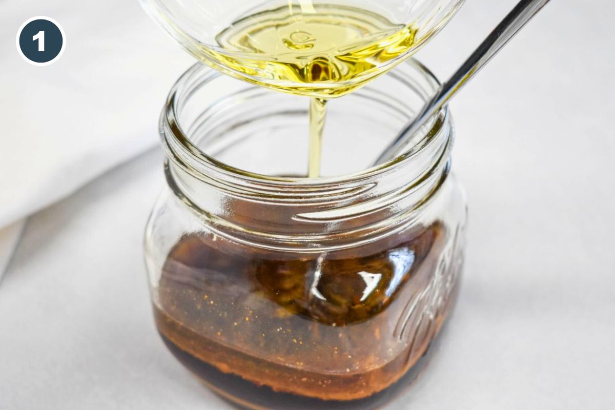 Pouring oil into a jar of soy-based sesame dressing for ramen noodle salad.