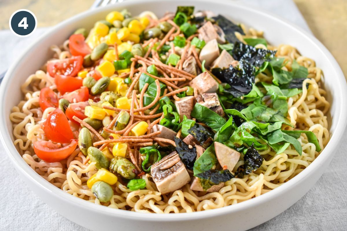 Prepared sesame ramen noodle salad in a bowl topped with vegetables and crunchy noodles.