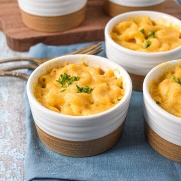 Close-up of a ramekin filled with baked mac and cheese, topped with parsley.