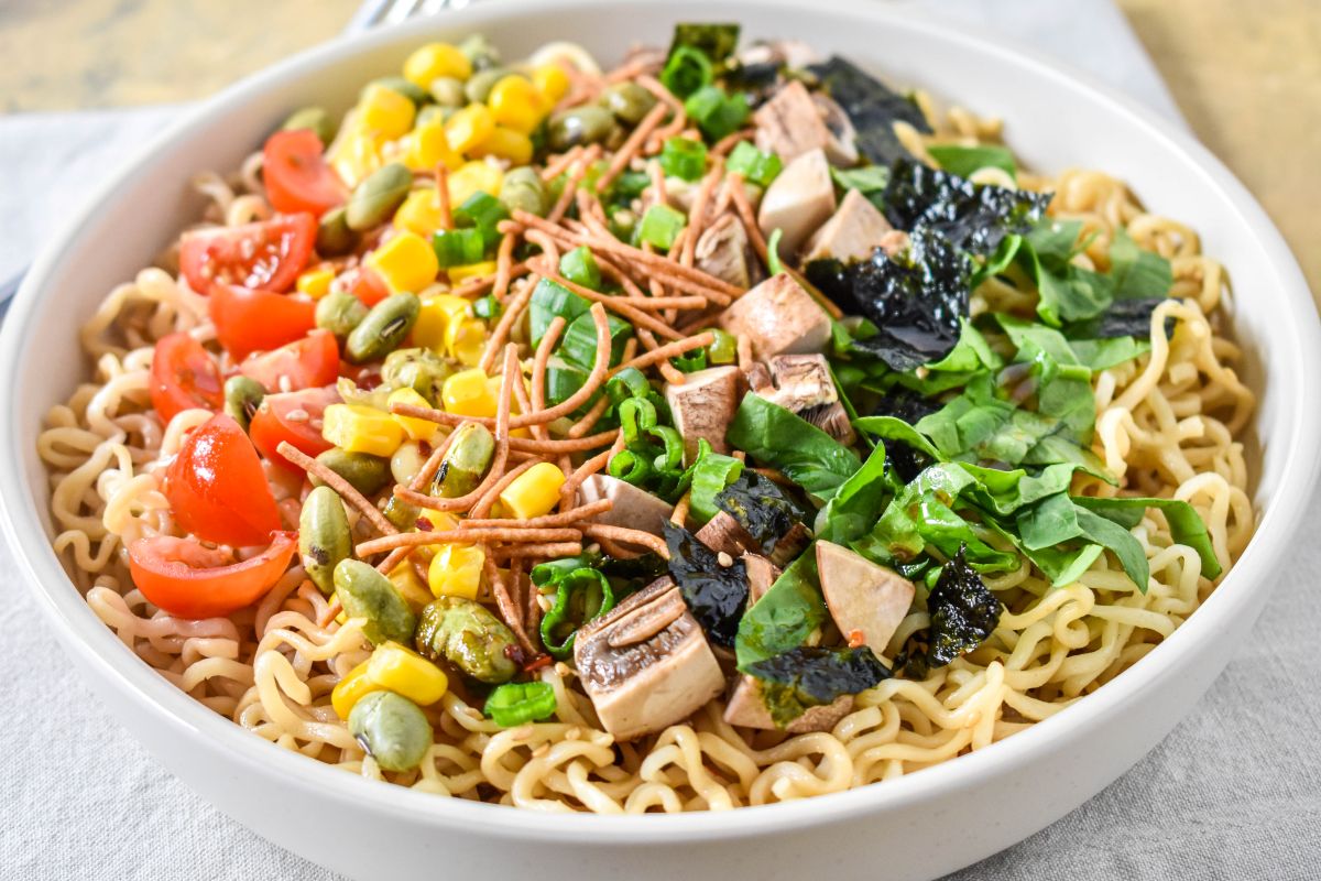 Close-up side view of sesame ramen noodle salad showing detailed textures of toppings and noodles.