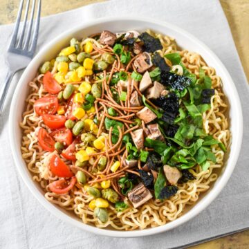 Overhead view of sesame ramen noodle salad with colorful toppings arranged in sections.
