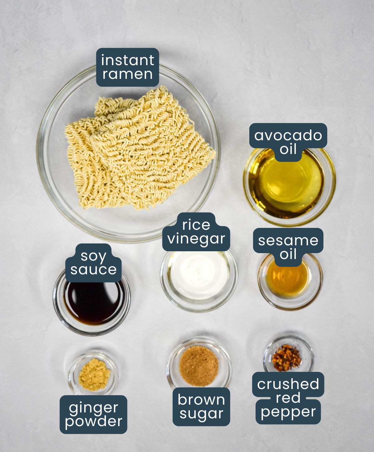 Labeled ingredients for sesame ramen noodle salad, including ramen, soy sauce, vinegar, oil, and spices.
