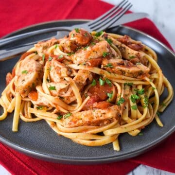 The chicken tomato pasta served on a gray plate with a red linen.