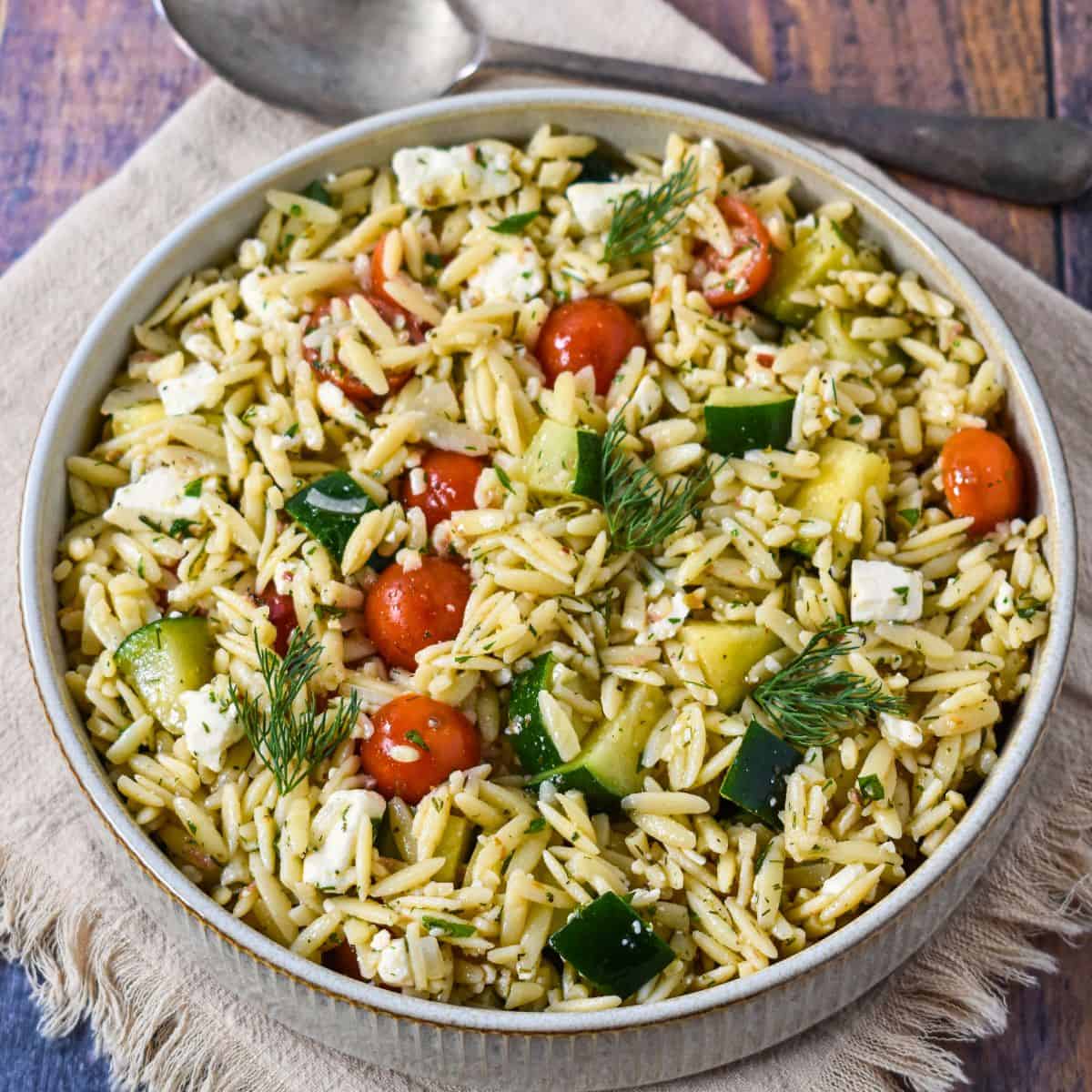 Close-up side angle of herb orzo salad in a bowl, highlighting texture and fresh ingredients.