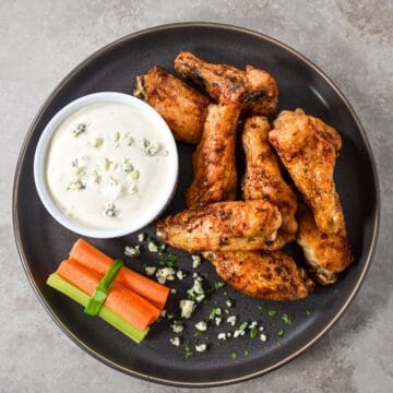 Plate of chicken wings with celery, carrots, and a bowl of homemade blue cheese dressing.