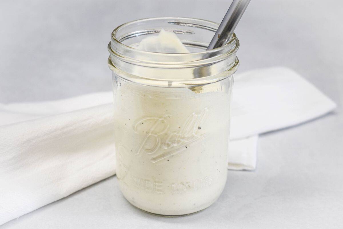 Blue cheese dressing after mixing, shown in a glass jar with a spoon.