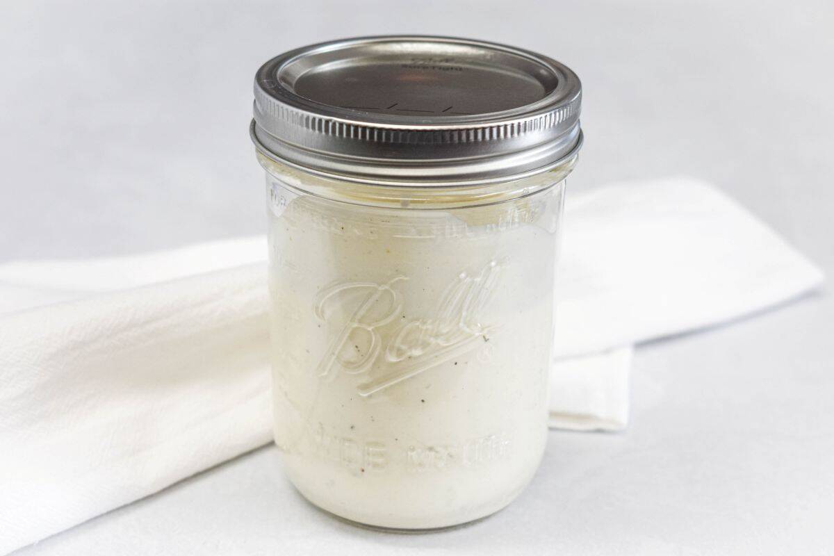 Finished dressing stored in a sealed mason jar on a white background.