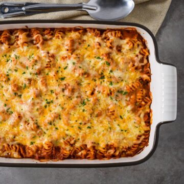 A close-up overhead shot of the entire vodka sauce pasta bake in a casserole dish, showing the bubbly, golden cheese topping.