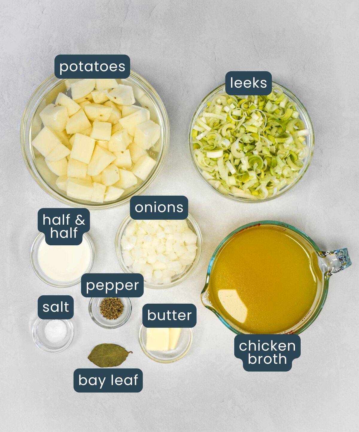 Ingredients for homemade soup including potatoes, leeks, onions, chicken broth, half and half, butter, bay leaf, salt, and pepper.