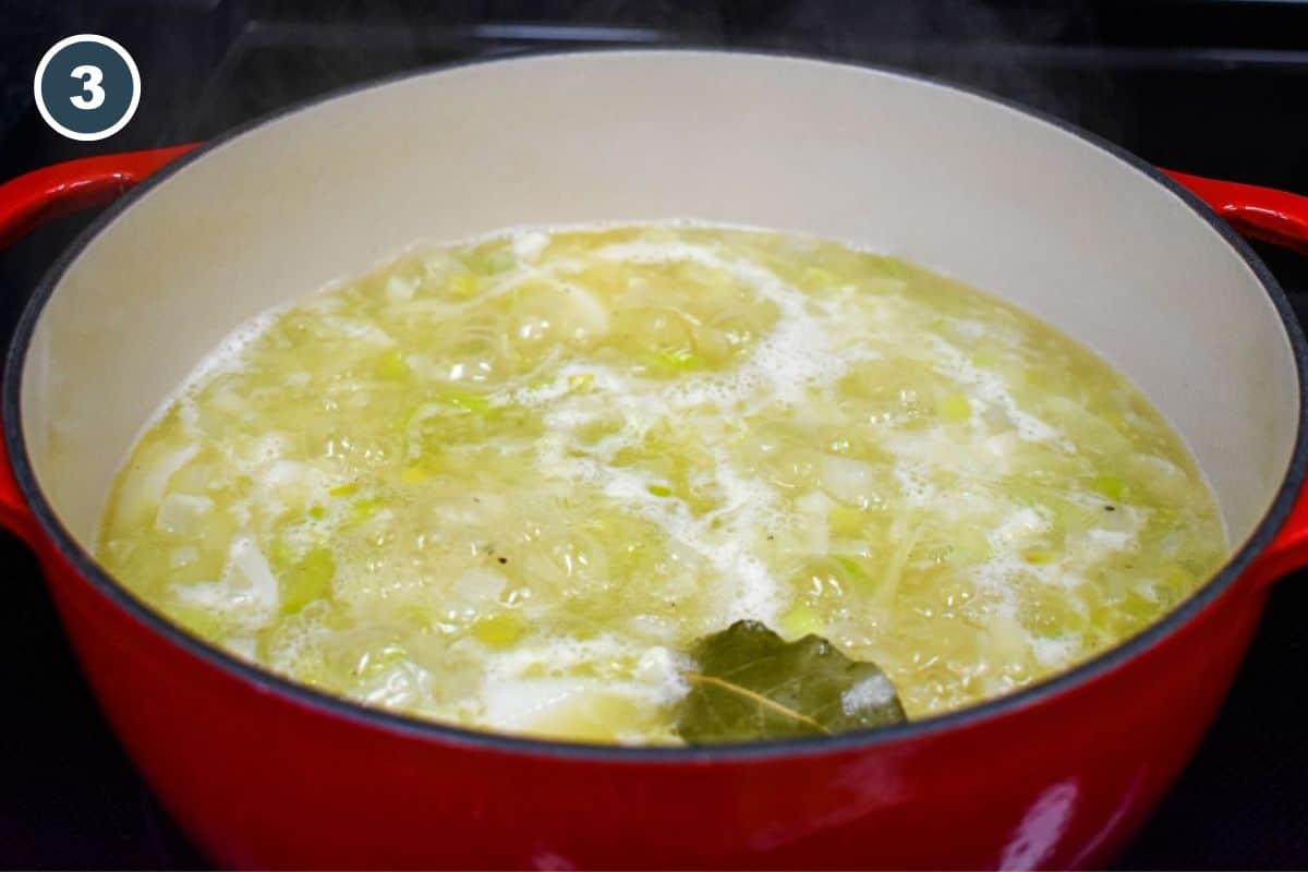 Potatoes, onions, and leeks simmering in broth with a bay leaf.