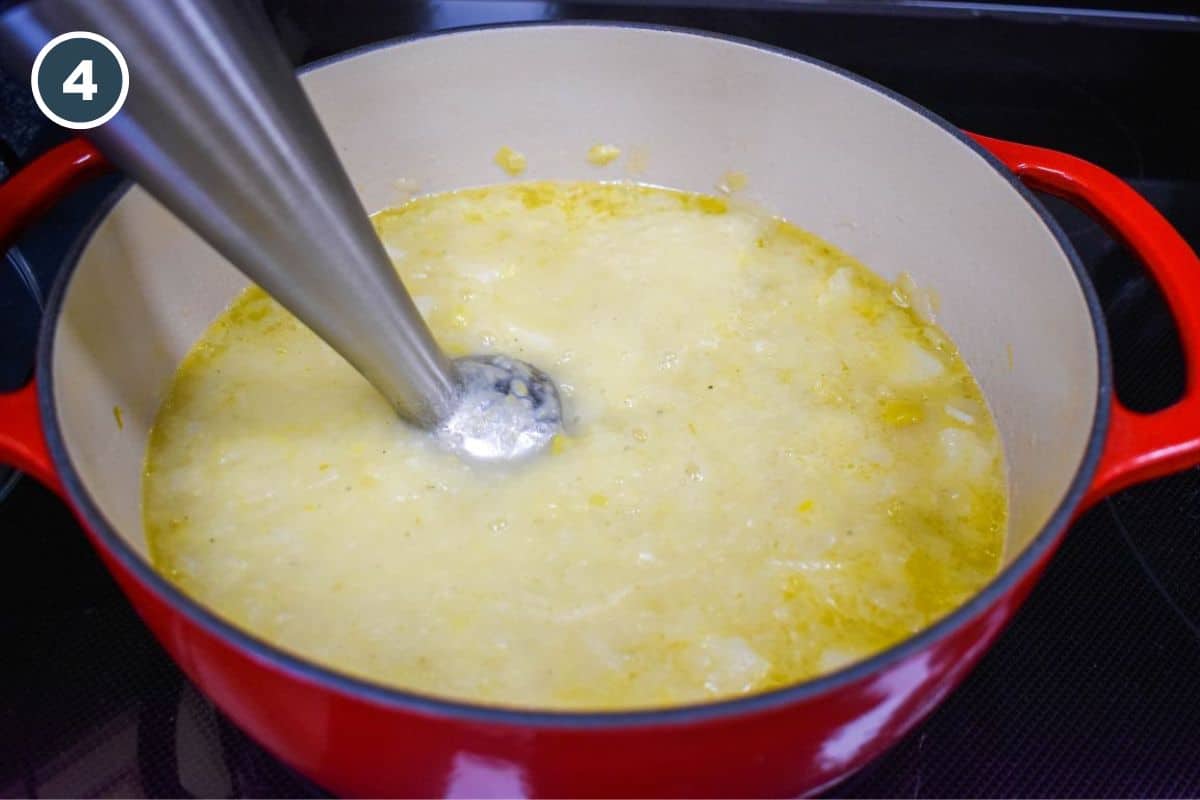 Blending the cooked potato and leek mixture with an immersion blender.