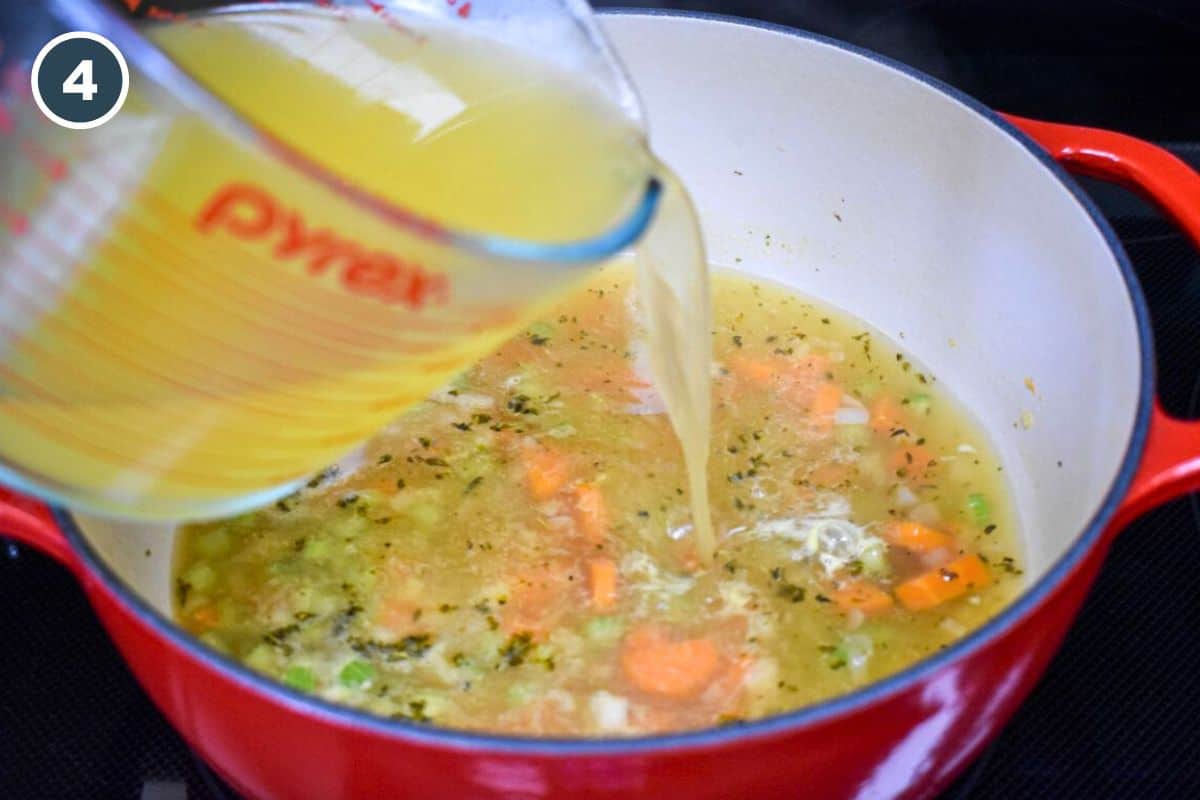 Pouring chicken broth into the pot with vegetables and herbs.