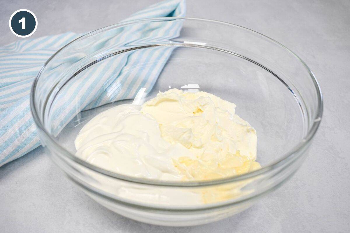 Glass mixing bowl with cream cheese, sour cream, and mayonnaise before mixing.