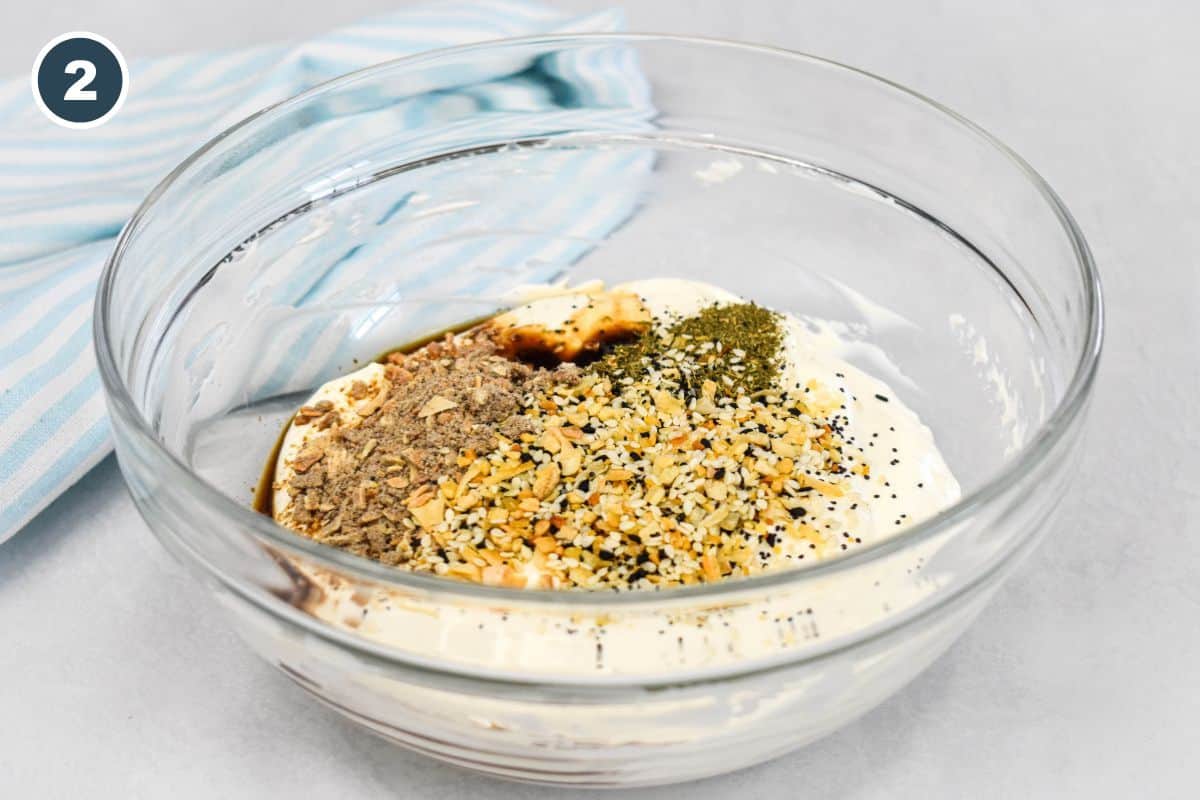 Mixing bowl with seasonings, dried dill, French onion soup mix, and Worcestershire sauce added to the creamy base.