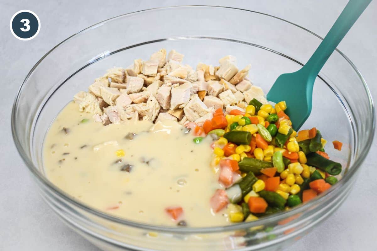 Cooked turkey, mixed vegetables, and the prepared sauce in a large mixing bowl before stirring.