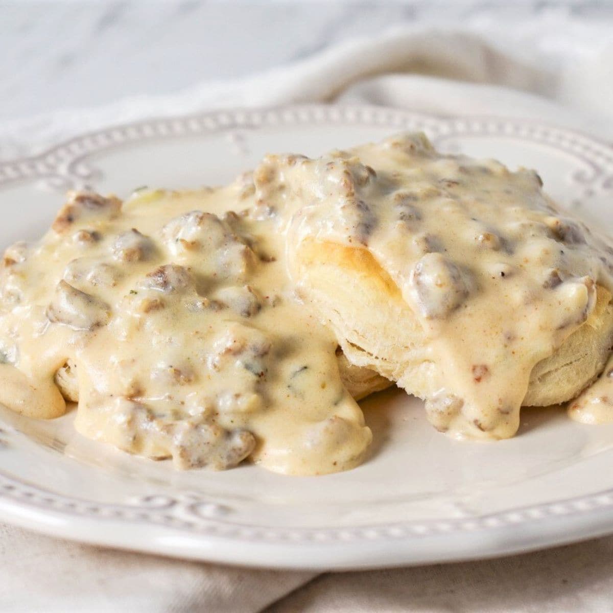 Sausage gravy served over biscuits on a white plate.