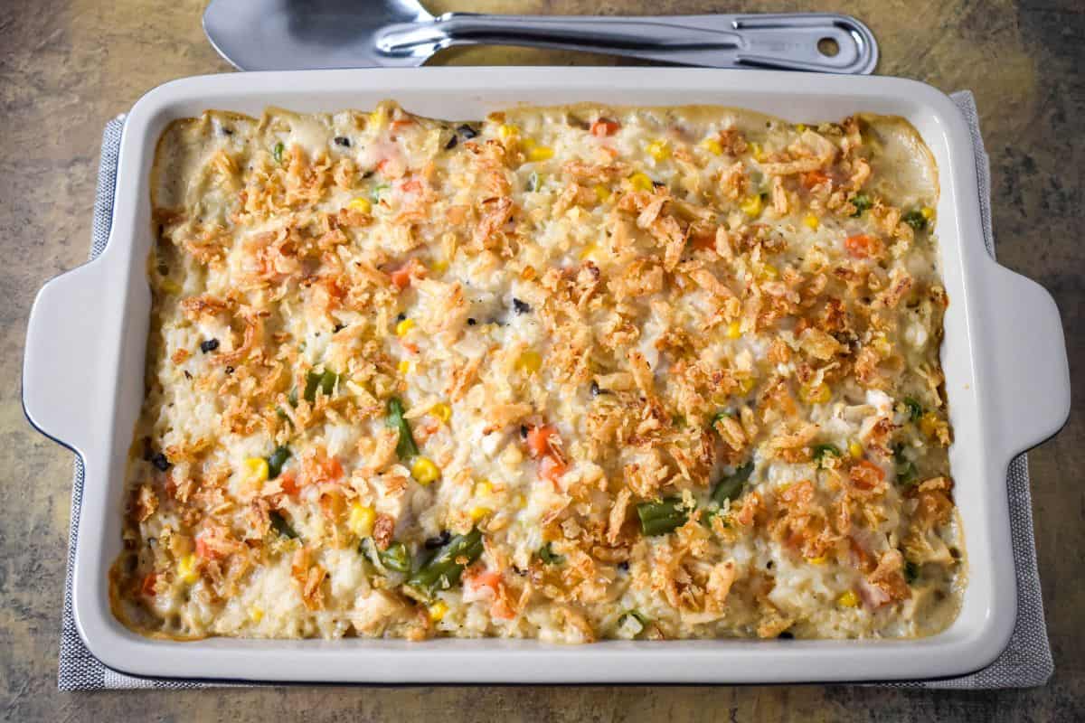 Overhead view of the baked casserole in a white dish, showing the golden onion topping and colorful vegetables.