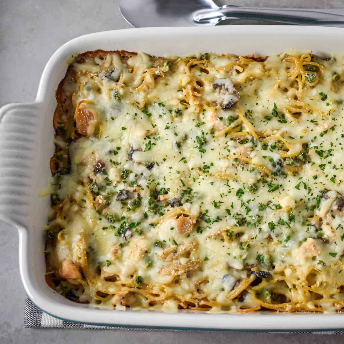 Baked casserole in a white dish topped with melted cheese and parsley.