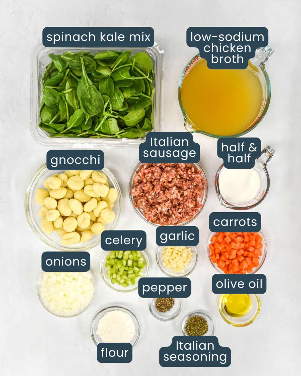 Labeled ingredients for the soup, prepped and arranged in glass bowls on a white table.