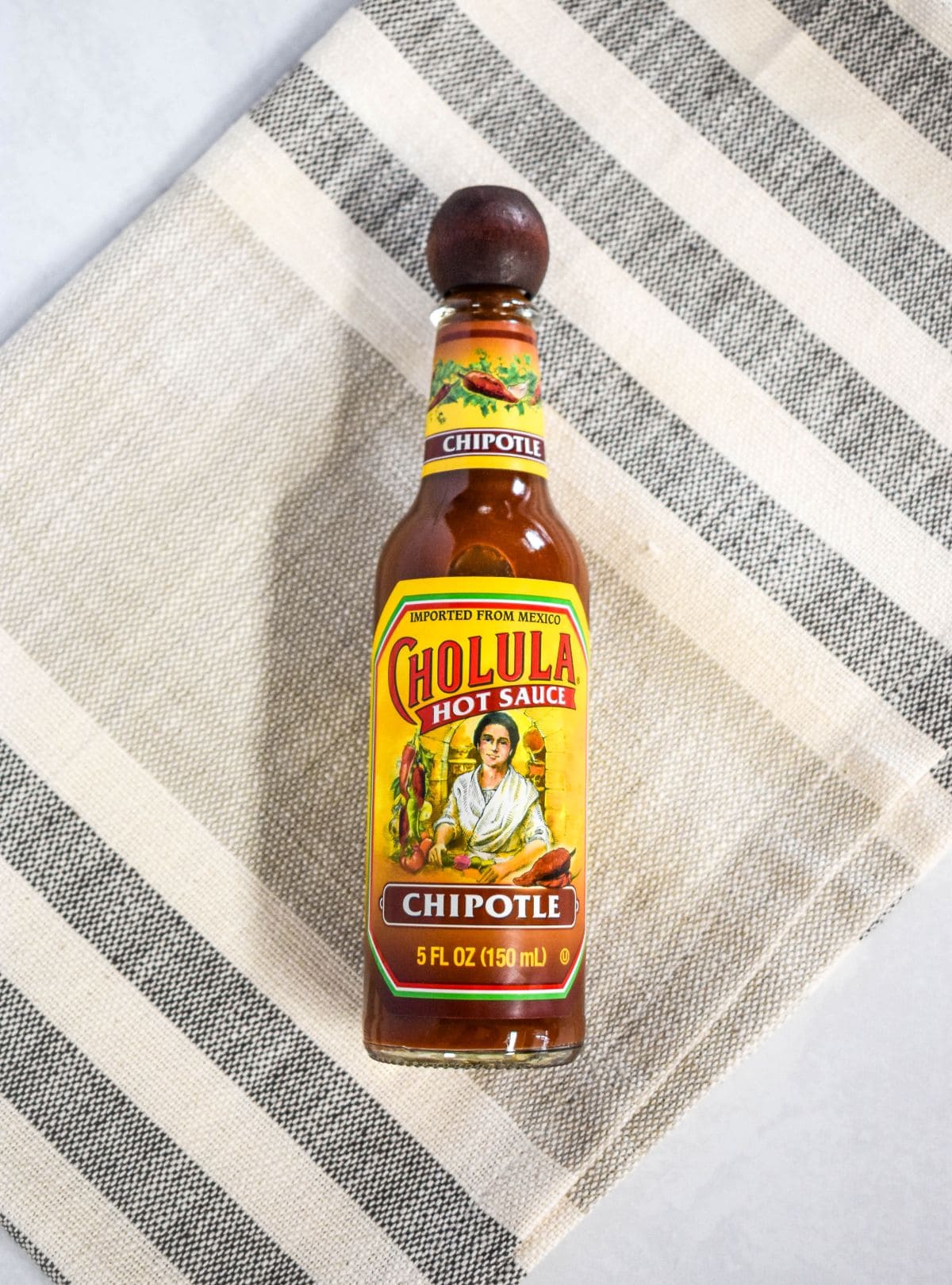 Bottle of chipotle hot sauce on a neutral surface, shown as the ingredient used for flavor and heat.