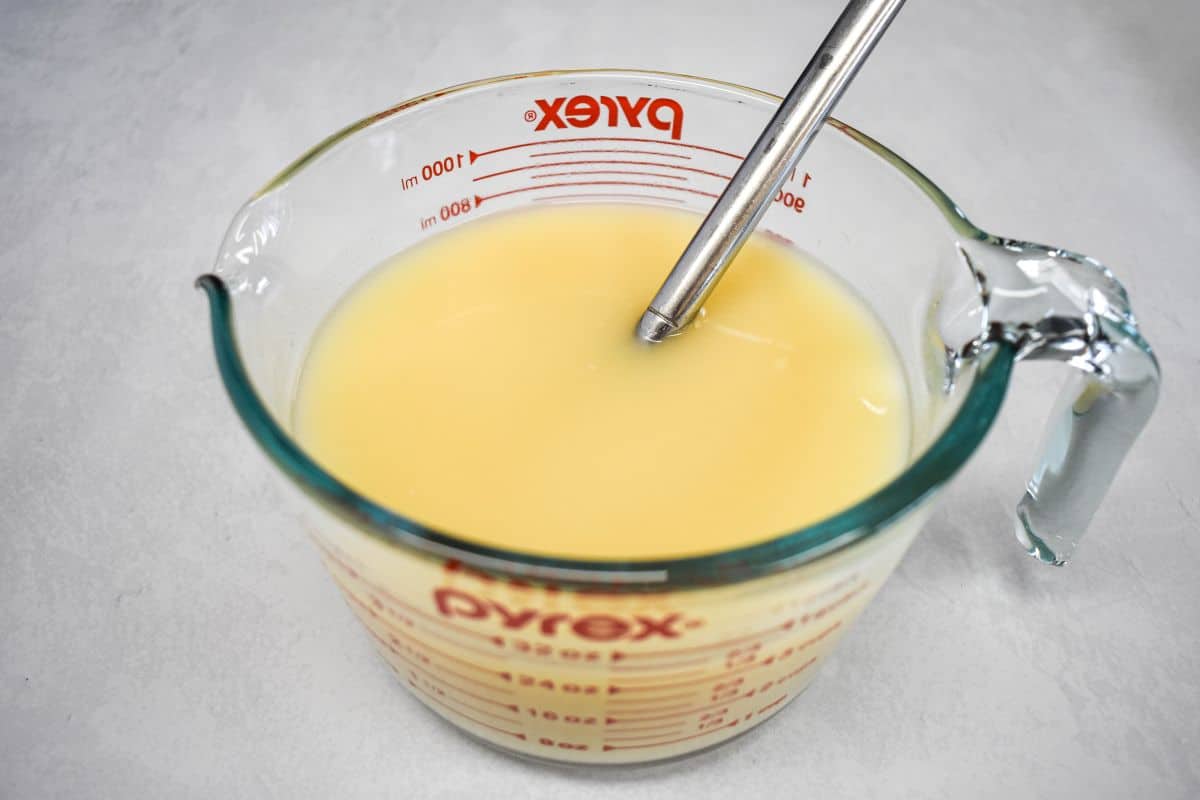 Cream of chicken soup and broth are whisked together in a glass measuring cup until smooth.