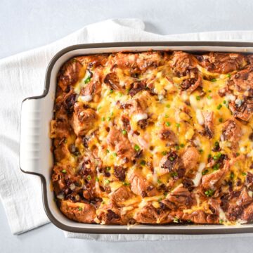 Bacon croissant breakfast casserole baked golden with melted cheese and crispy bacon in a baking dish.