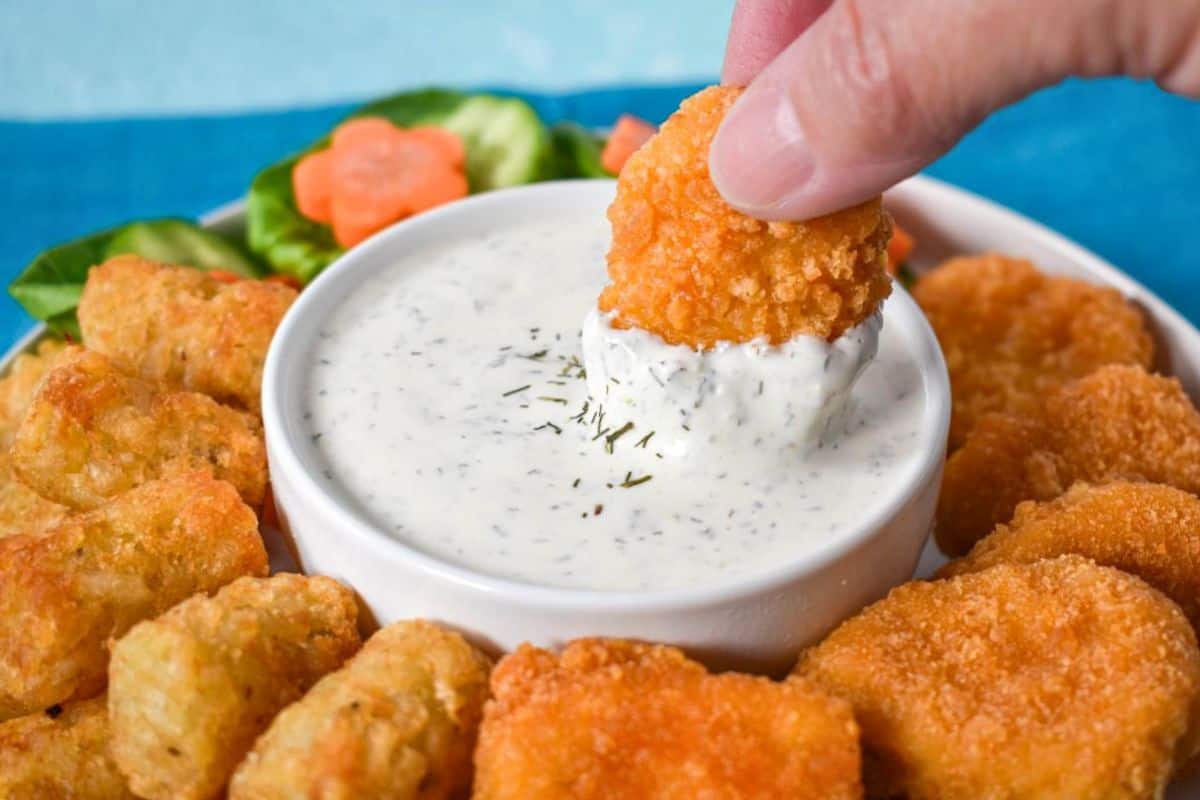 Close-up of a chicken nugget dipped into ranch dressing.