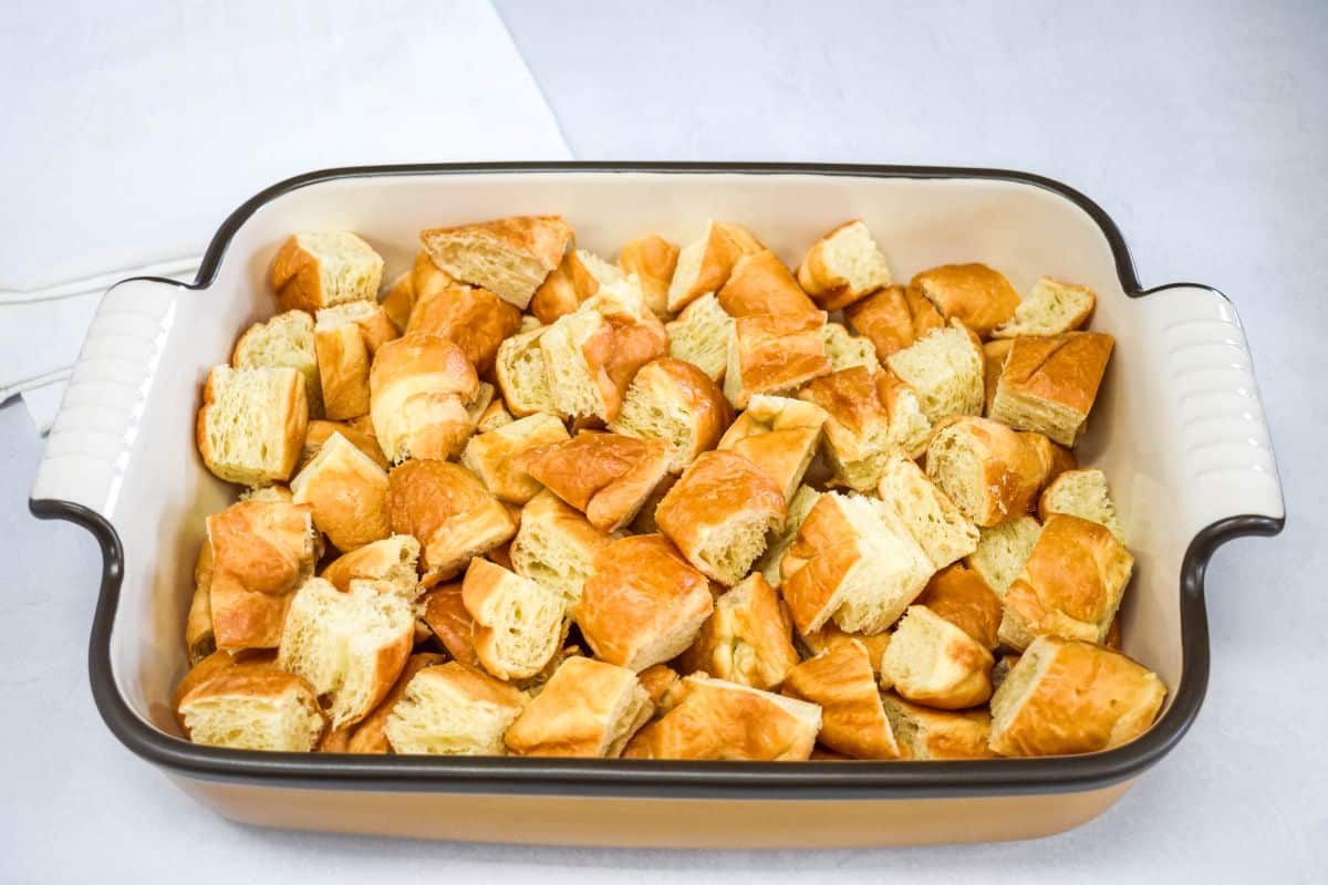 Cut croissants arranged in a greased baking dish in an even layer.
