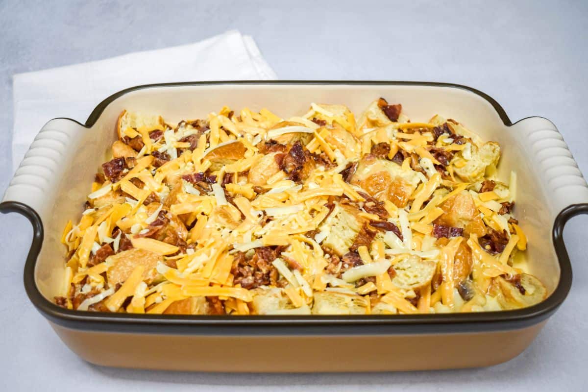 Egg mixture poured over the croissant, bacon, and cheese mixture in the baking dish.