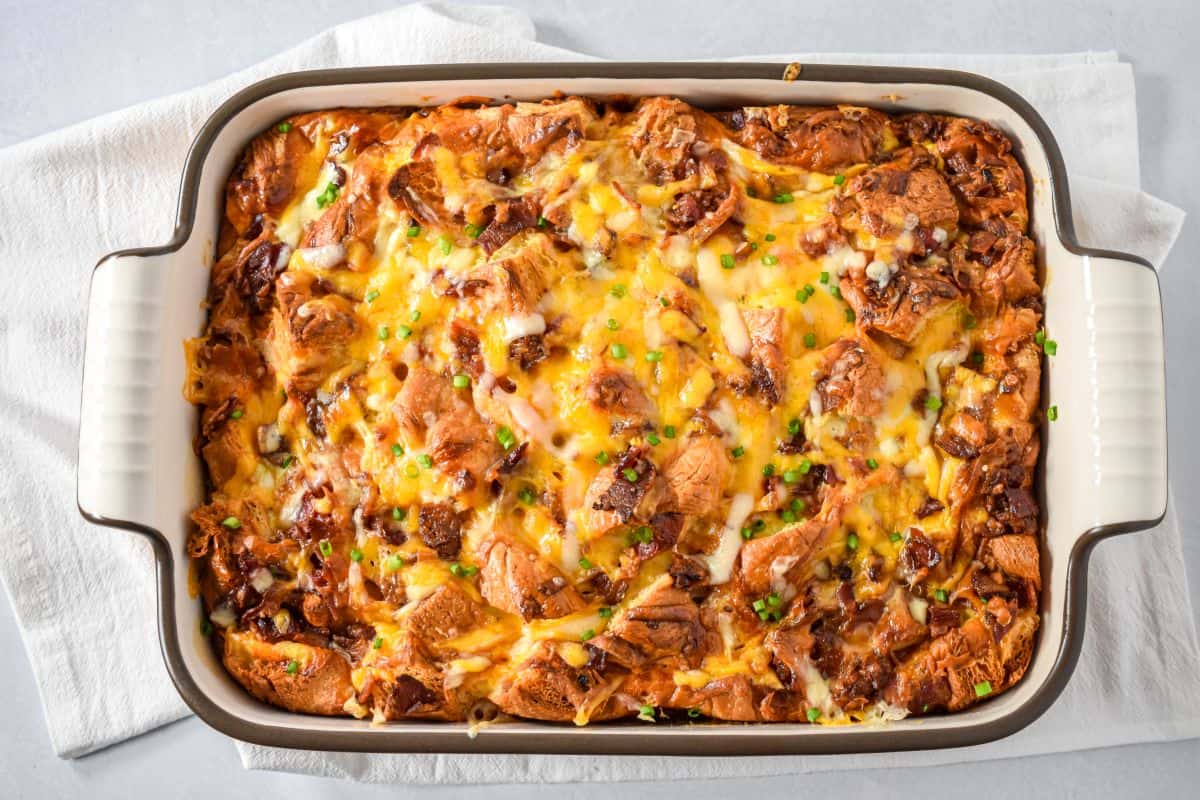 Baked croissant breakfast casserole golden brown and topped with melted cheese and chives.